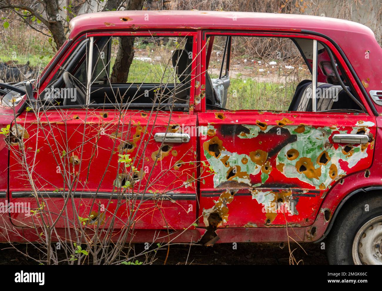 Auf Dem Land. Zerstörtes ziviles Auto steht am Straßenrand (Nahaufnahme). Löcher von Kugeln und Splittern an der Karosserie des Autos. Krieg in der Ukraine Stockfoto