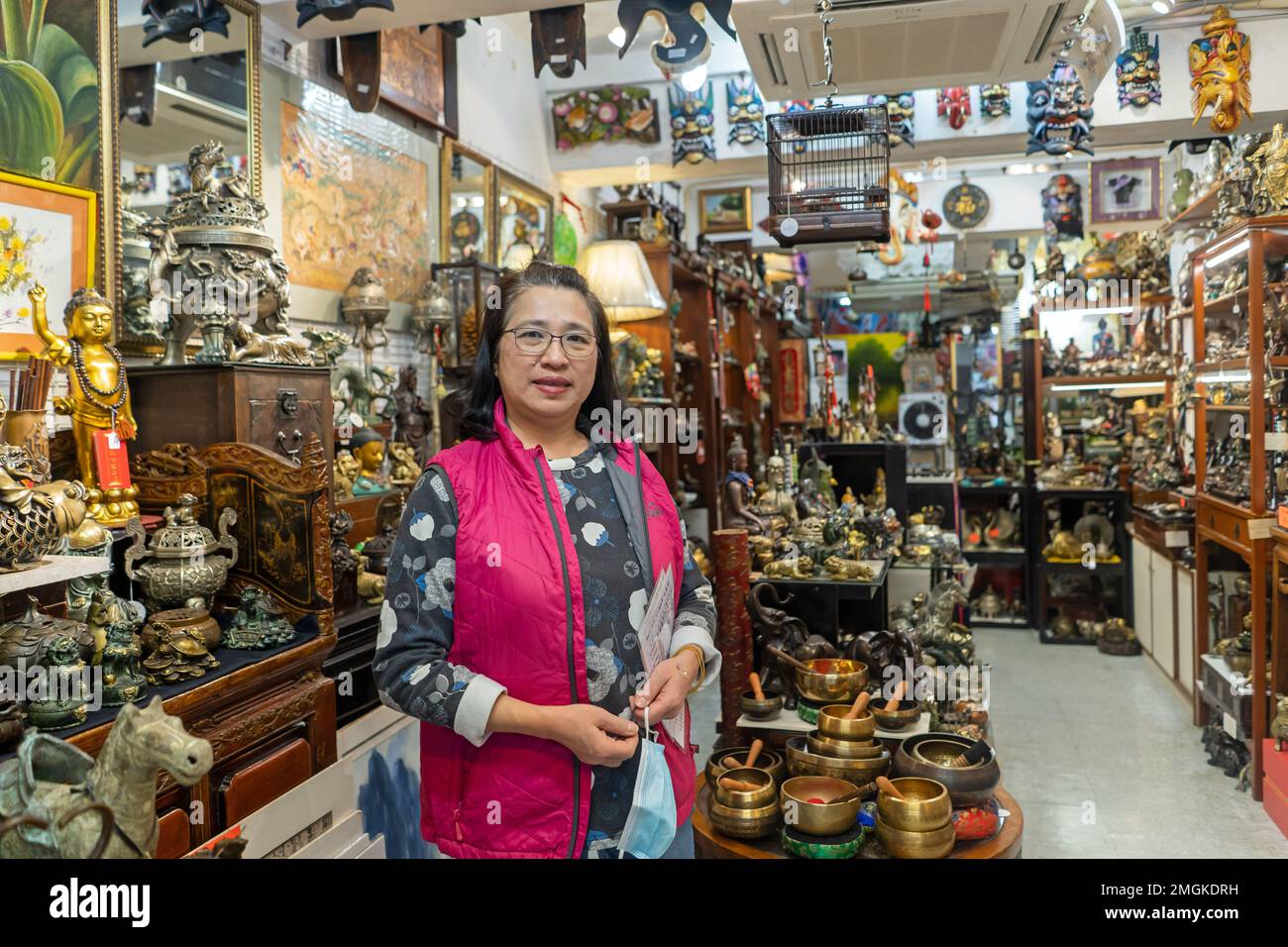 Hongkong - 2022. Dezember Porträt einer Frau, die ein Antiquitätengeschäft in Stanely Market betreibt Stockfoto