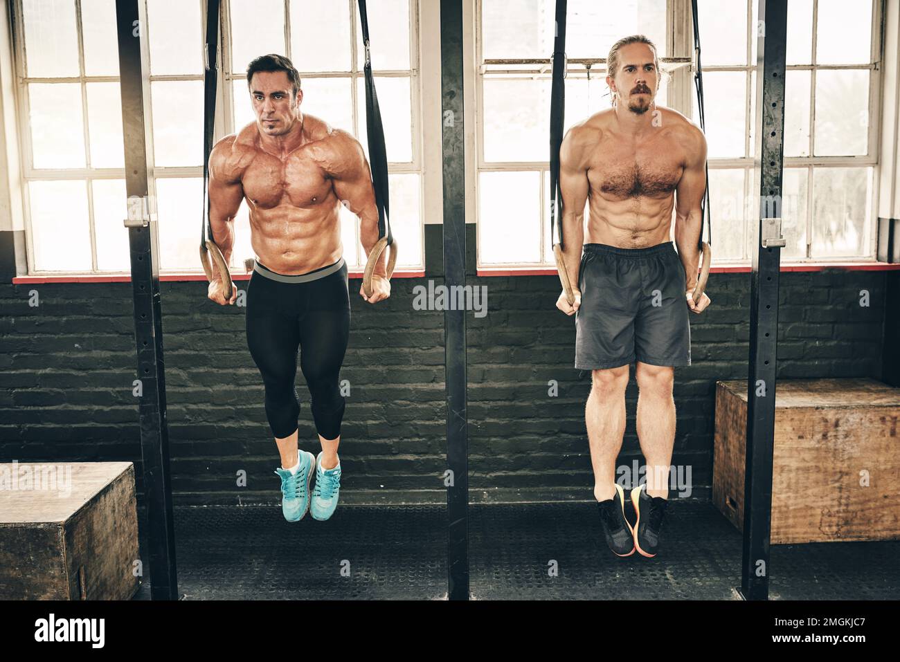 Nur noch ein bisschen. Zwei fitte und entschlossene junge Männer, die gemeinsam im Fitnessstudio trainieren, nutzen die Zugstange. Stockfoto