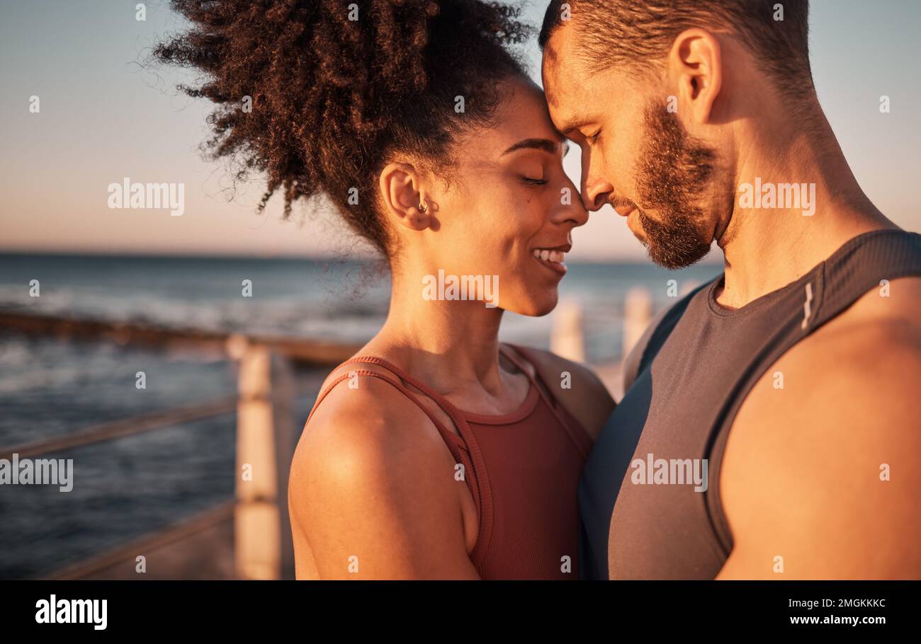 Schwarzes Paar, lächeln und umarmen mit Stirn am Strand, die Beziehung, Mitgefühl oder Liebe und Fürsorge umarmt. Glücklicher Mann und glückliche Frau, die lächelnde Köpfe berührt Stockfoto