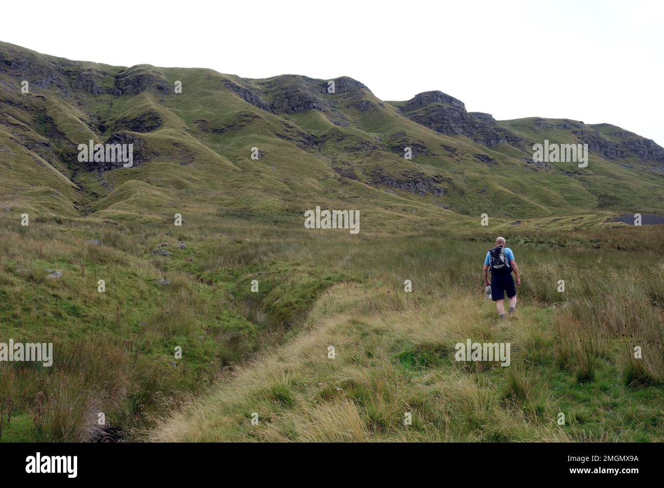 Mann, der an den Crags am Mallerstang Edge von Outhgill zum High Seat am Mallerstang Common im Eden Valley, Yorkshire Dales National Park, Großbritannien, vorbeigeht. Stockfoto