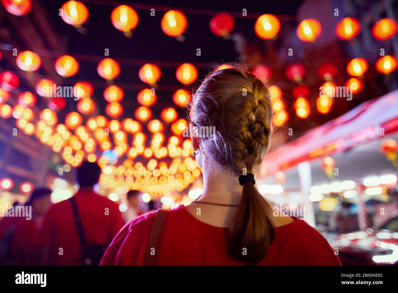 Eine Touristenfrau in rotem Hemd, die die Dekoration des Nachtmarkts mit roten Laternen für das chinesische Neujahr in Bangkok Chinatown in Thailand ansieht Stockfoto