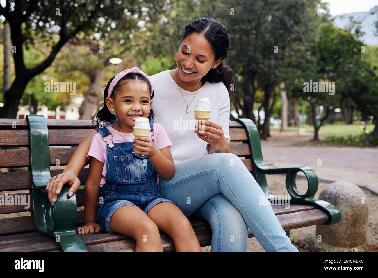 Schwarze Familie, Park und Eis mit Mutter und Tochter, die sich auf einer Bank in der Natur zusammentun. Sommer, Kinder und Garten Stockfoto