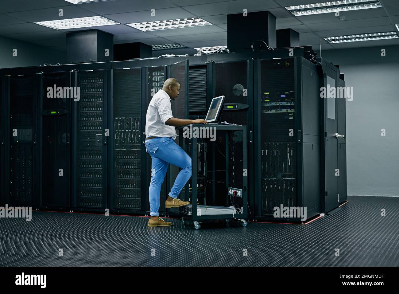 Sie ist in allen Dingen geschult. Ein IT-Techniker, der einen Computer verwendet, während er in einem Rechenzentrum arbeitet. Stockfoto