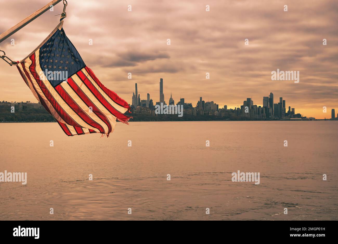 amerikanische Flagge und malerischer Blick auf die Skyline von Manhattan, New York bei Sonnenuntergang vom Hudson River in Edgewater, New Jersey Stockfoto