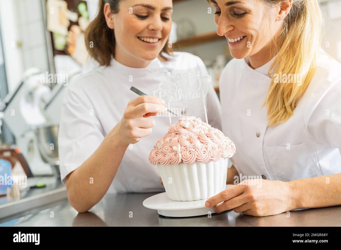Süßigkeiten schmücken große Kuchen-Muffins mit Süßigkeiten und Pinzetten in der Bäckerei Stockfoto