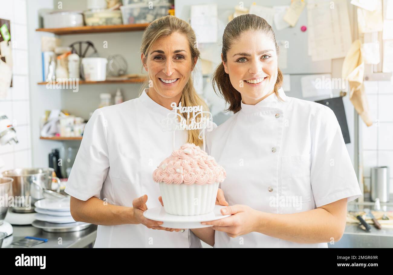Süßwarenlächelnde und große Geburtstagskuchen-Muffins mit Süßigkeiten in der Bäckerei Stockfoto