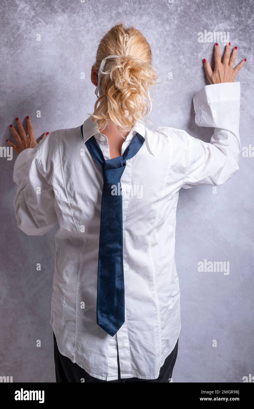 Eine blonde Frau, hinten zugeknöpft mit einer blauen Krawatte, von hinten gesehen Stockfoto