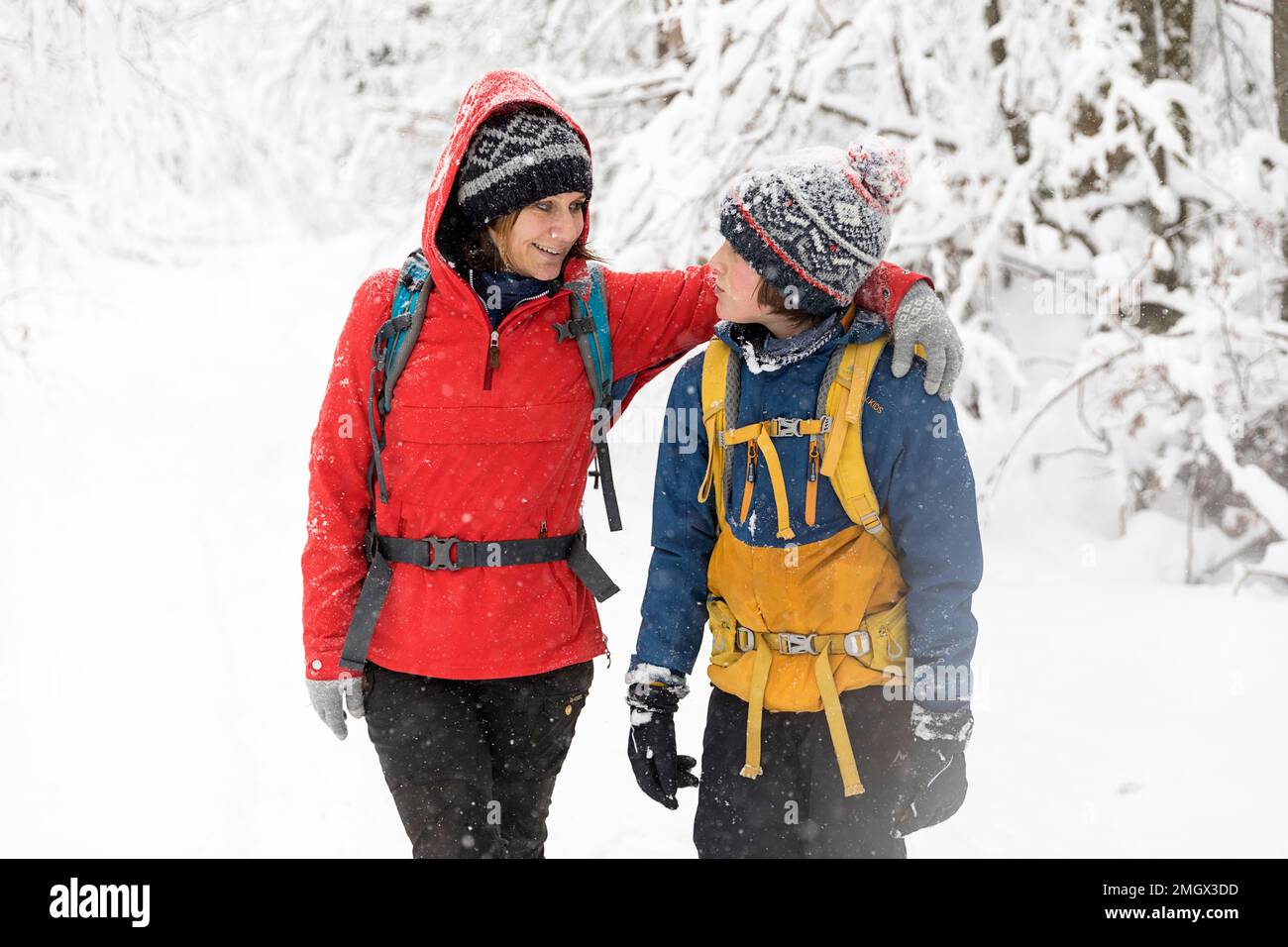 Mutter und Sohn haben Spaß beim Wandern im Winter während des Schneefalls in den Urwäldern der Region Notranjska, Dolenjske toplice, Slowenien Stockfoto