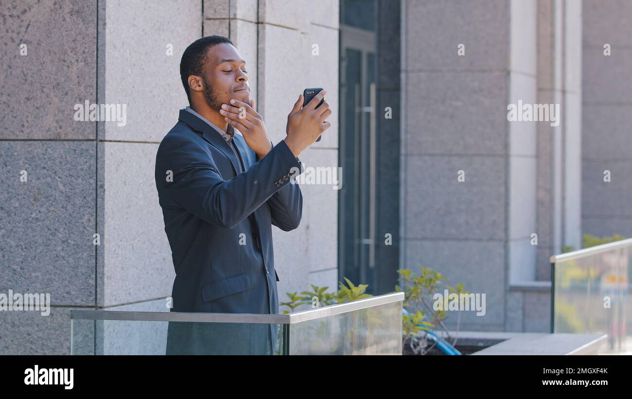 Ein afroamerikanischer Büroangestellter, der auf dem Balkon steht, fotografiert einen Videoblog und macht ein Selfie-Foto für einen Vlog-Blogger, der mit Followern spricht Stockfoto