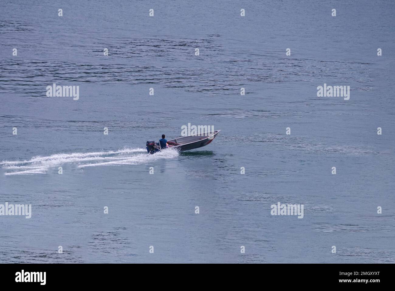 Ein Fischer fährt auf einem Boot an einem Strand in Batam Stockfoto
