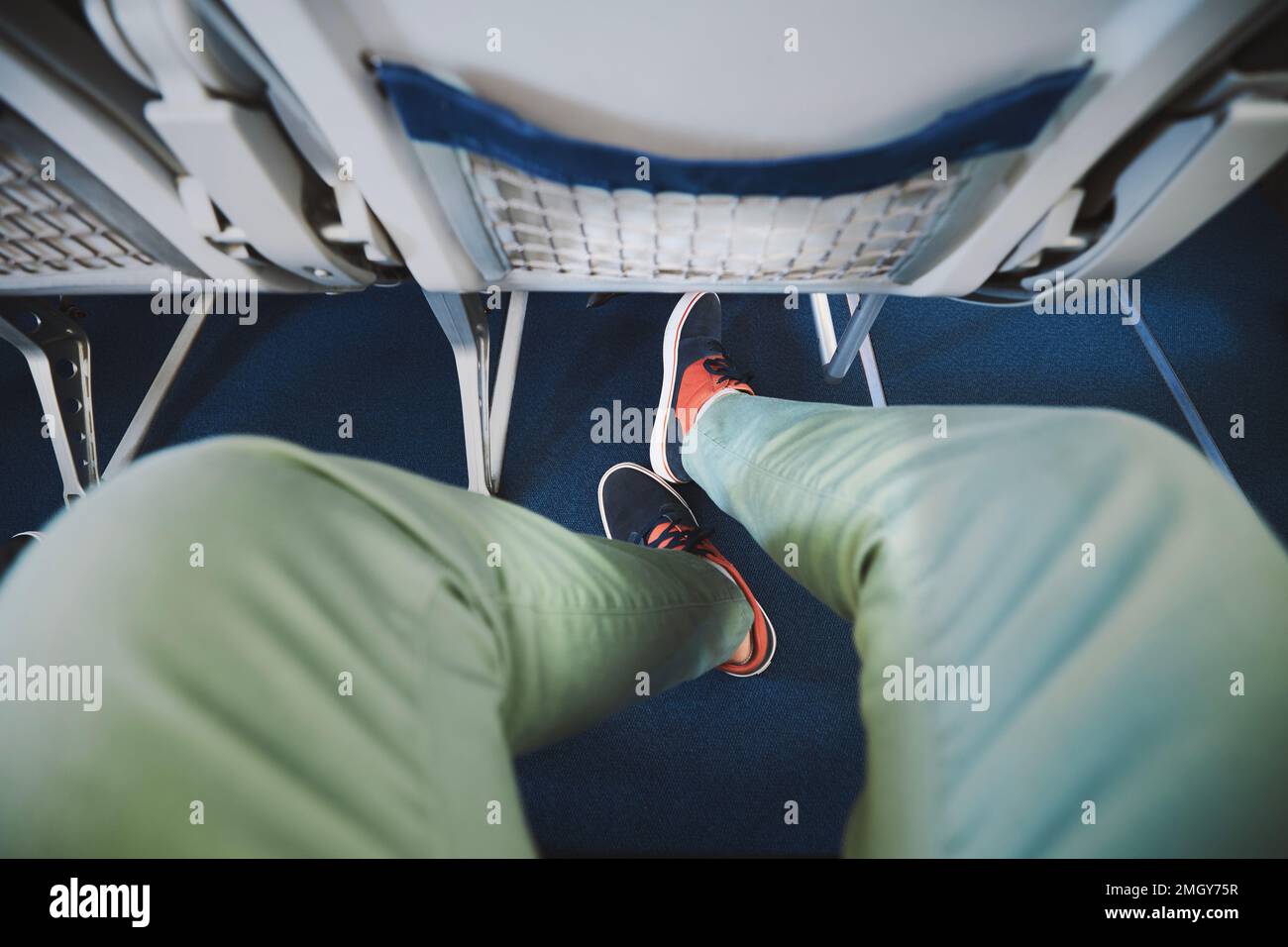 Persönliche Perspektive auf Beinfreiheit zwischen Sitzen im Flugzeug. Mann ruht sich während des Fluges aus. Stockfoto