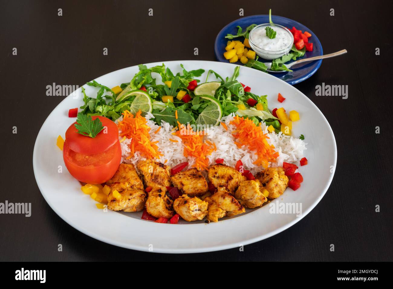 Jooje Kebab aus Kalbfleisch mit Reis, Gemüse und Sauce auf schwarzem Hintergrund. Stockfoto