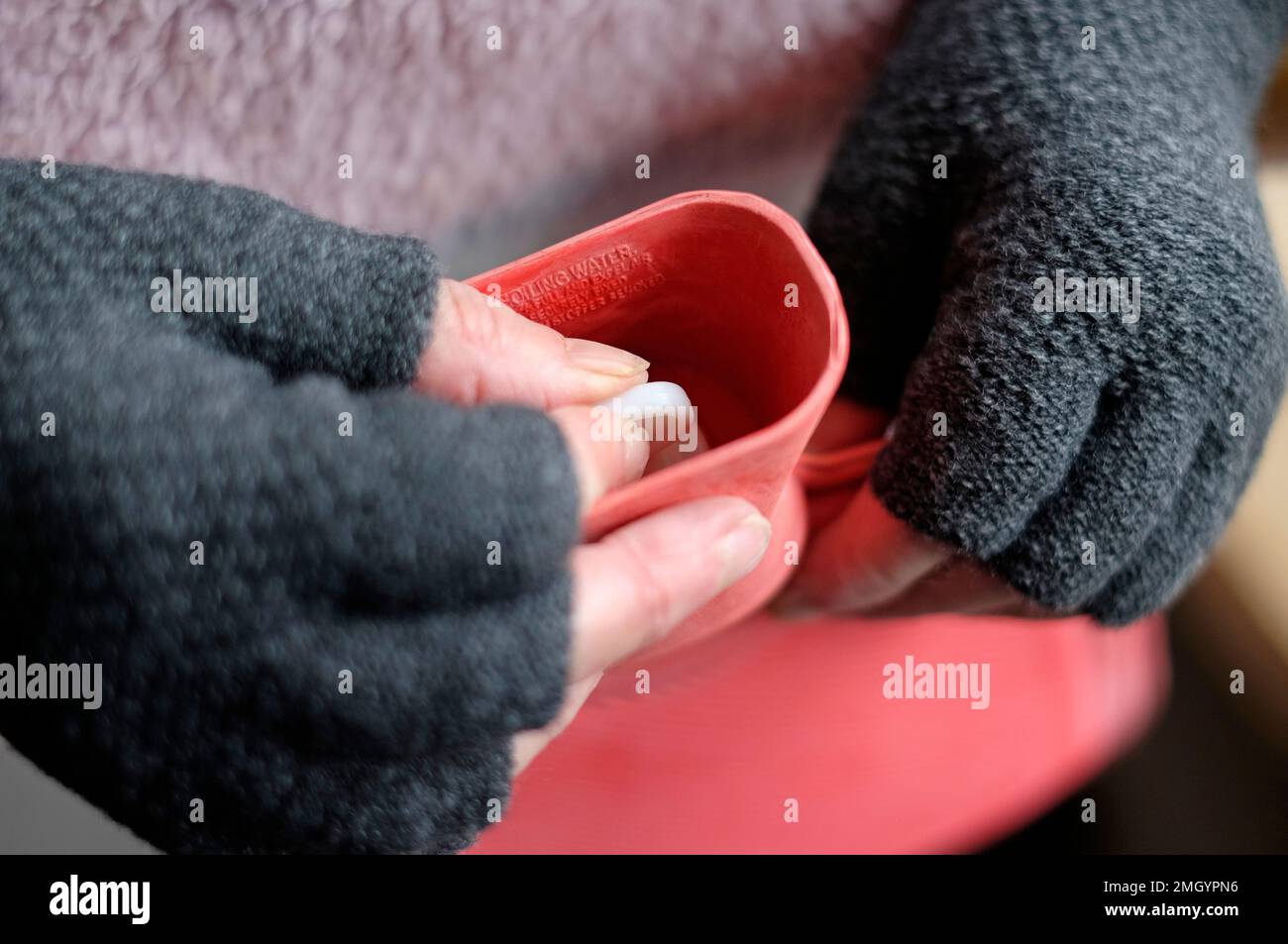 Seniorin, die den Stopfen der Heißwasserflasche festzieht Stockfoto