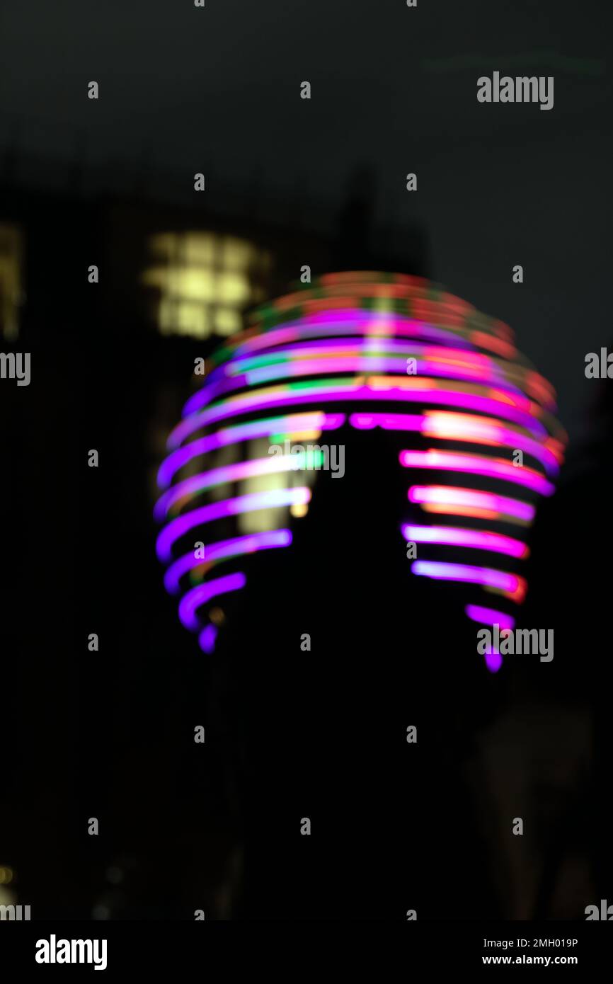 Fotoverschwommene elektrische Lampen an der Anlage auf der Straße von Vilnius und die Silhouette eines Mannes bei Nacht Stockfoto