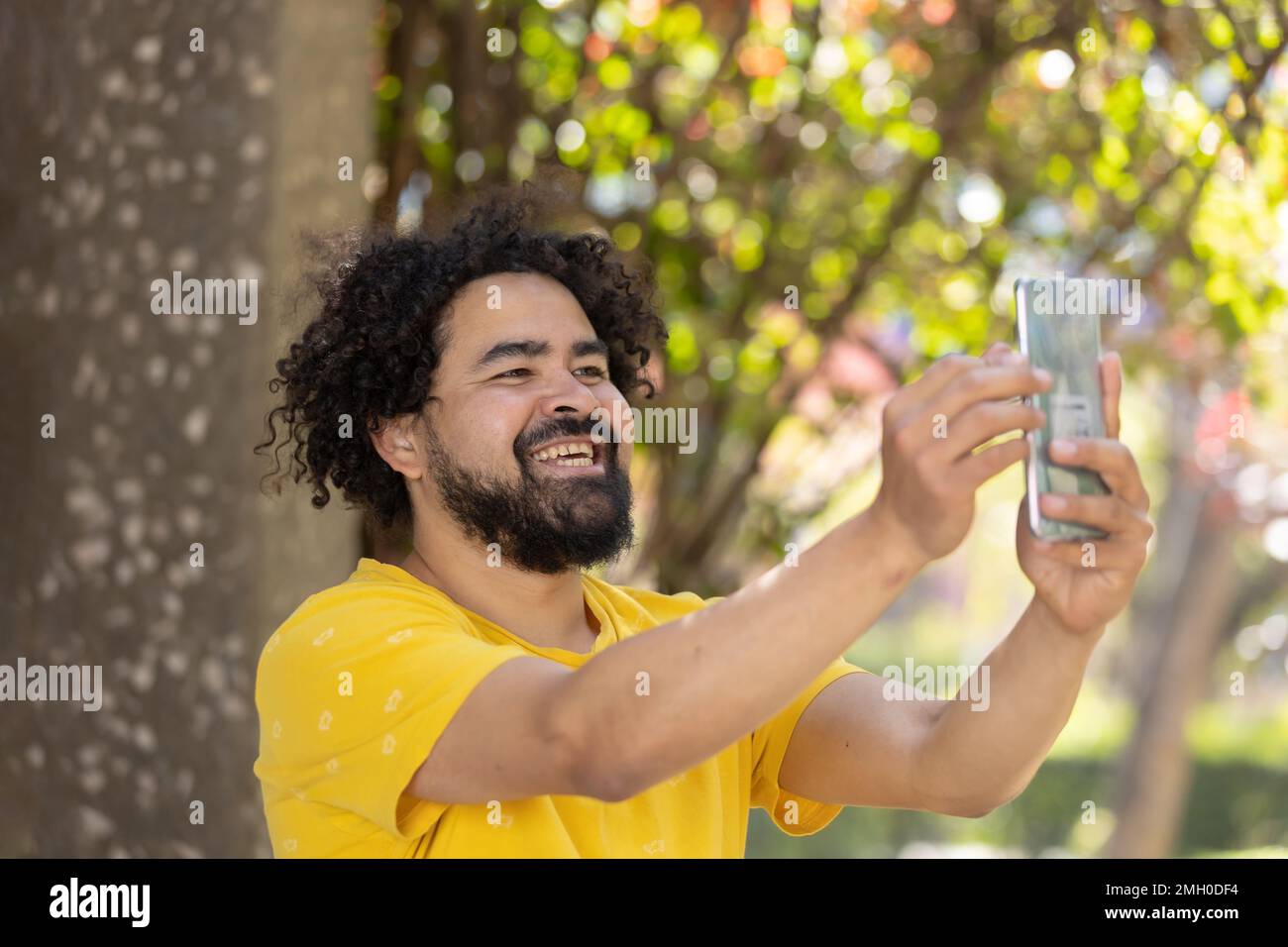 Porträt eines Mexikaners, der mit Afro und Bart lächelt und Selfie macht Stockfoto