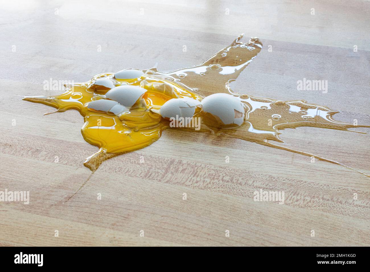Horizontaler Schuss eines heruntergefallenen und zerbrochenen weißen Hühnereies auf den Boden mit Kopierraum. Stockfoto
