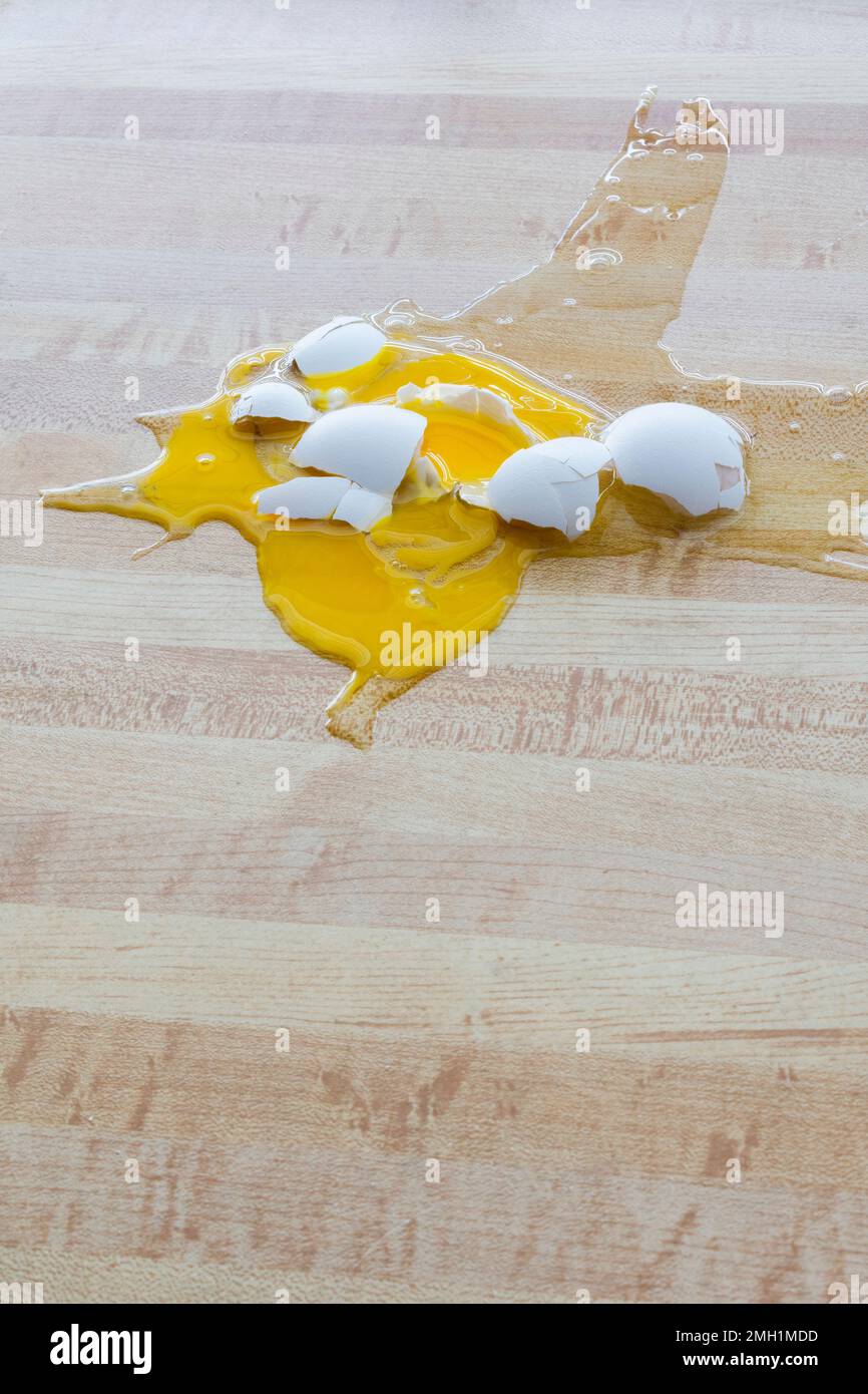 Vertikale Aufnahme eines zerbrochenen weißen Hühnereis auf dem Boden mit Kopierraum. Stockfoto