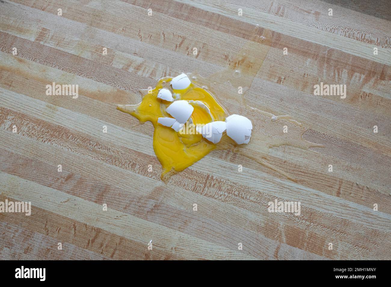 Horizontaler Schuss eines zerbrochenen weißen Hühnereies auf den Boden mit Kopierraum. Stockfoto