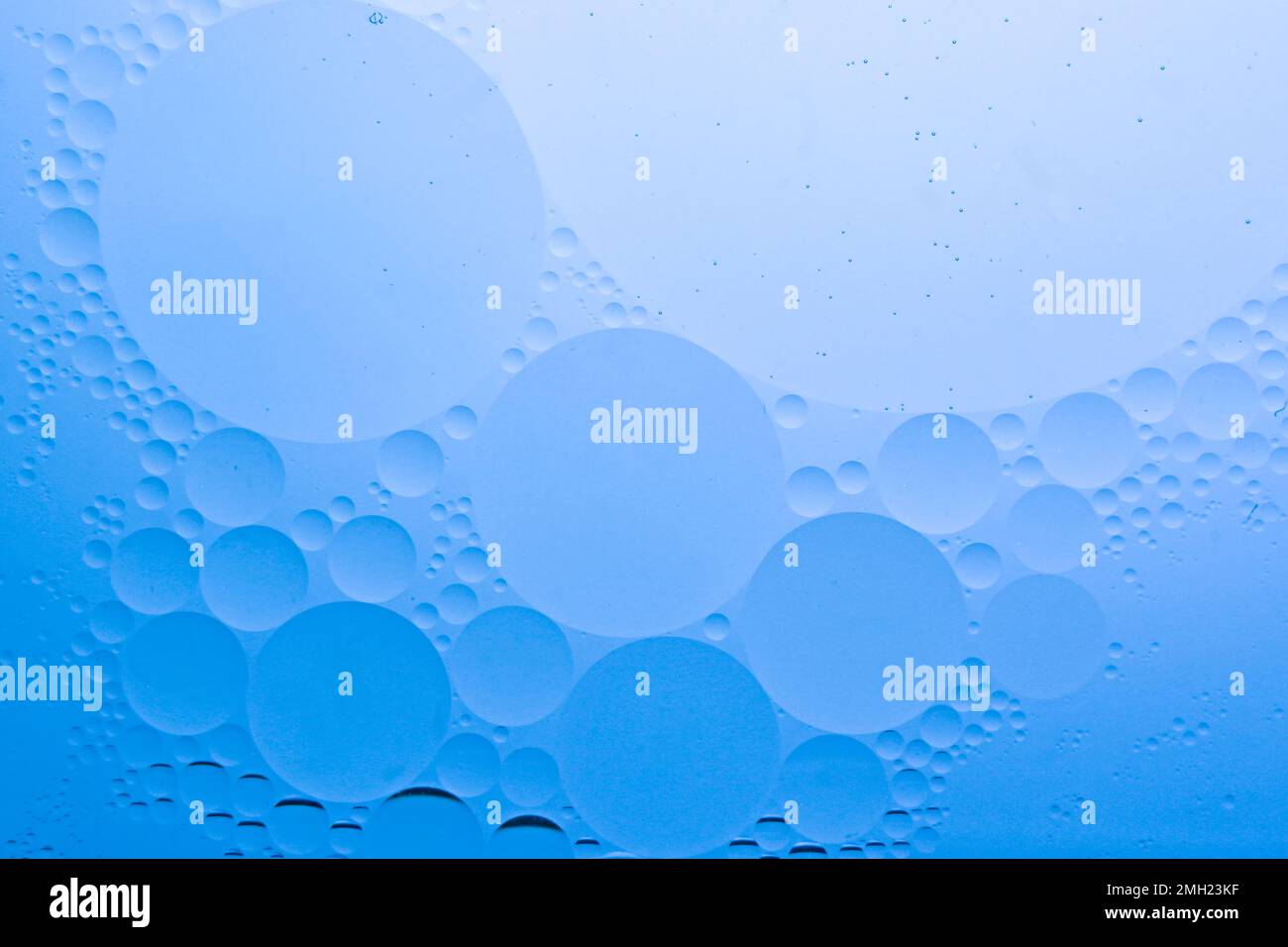 Ölblasen auf dem Wasser mit blauem Hintergrund für kosmetische flüssige Schönheitsprodukte. Gesichts-Serum-Hintergrund Stockfoto