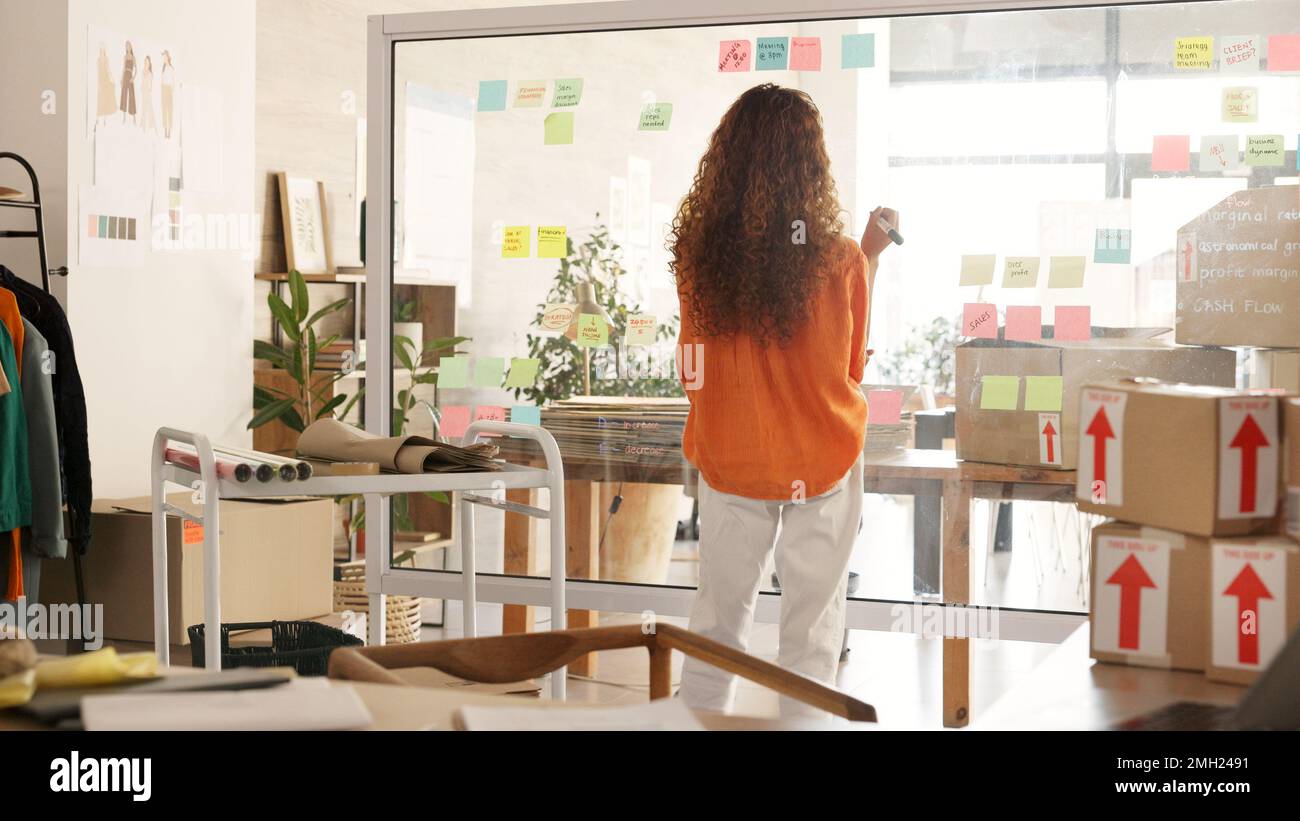 Planung, Logistik und Versand mit einer schwarzen Zustellerin, die in ihrem Büro auf ein Glasbrett schreibt. Marketing, Supply Chain und E-Commerce mit Stockfoto