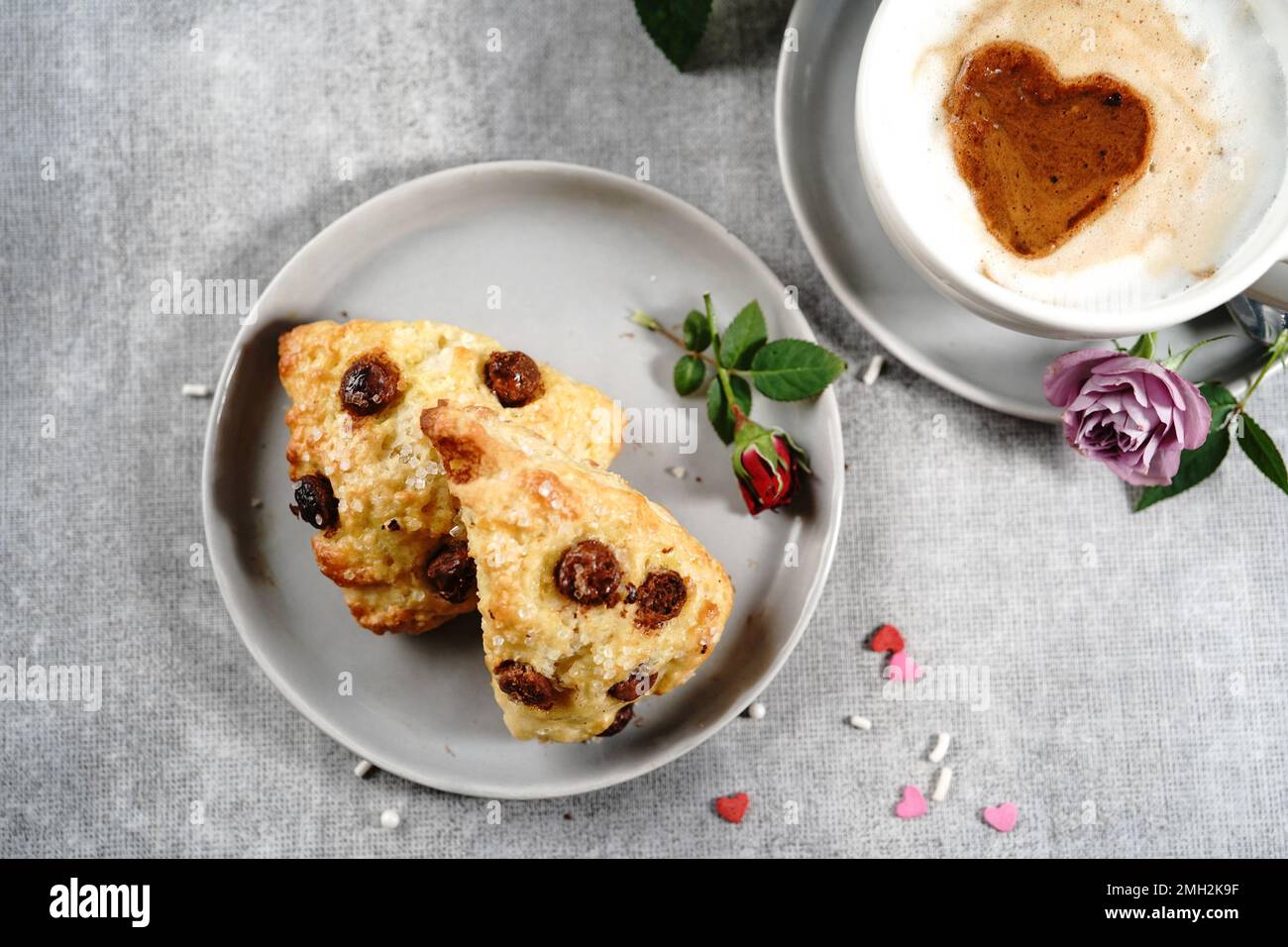 Frühstücksraum am Valentinstag - Scones Cappuccino Herz und Rosen auf einem Tablett, selektiver Fokus Stockfoto