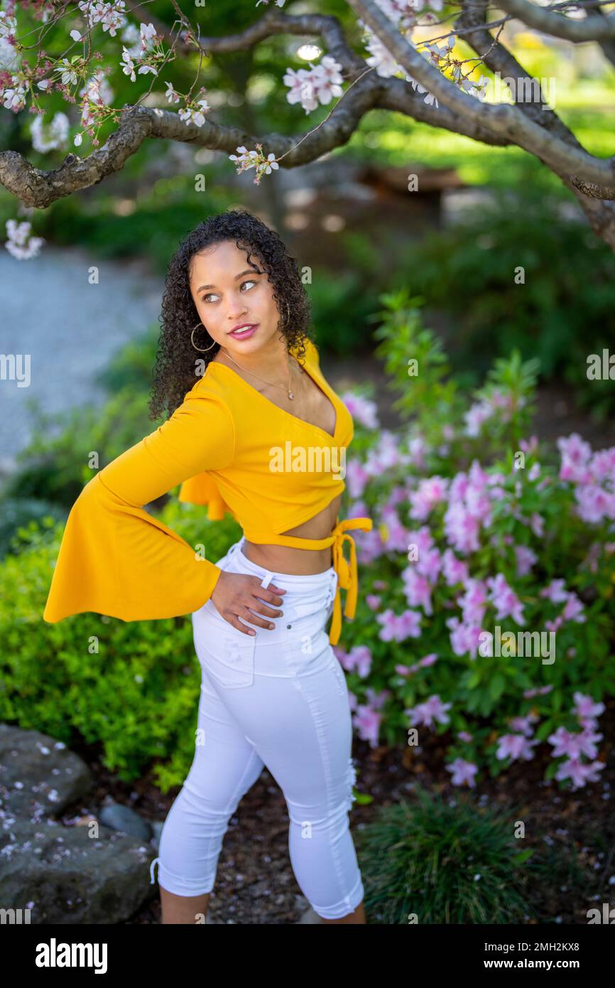 Down-Angle-Porträt einer glücklichen jungen afroamerikanischen Frau in einem blühenden Garten im japanischen Stil im Frühling Stockfoto