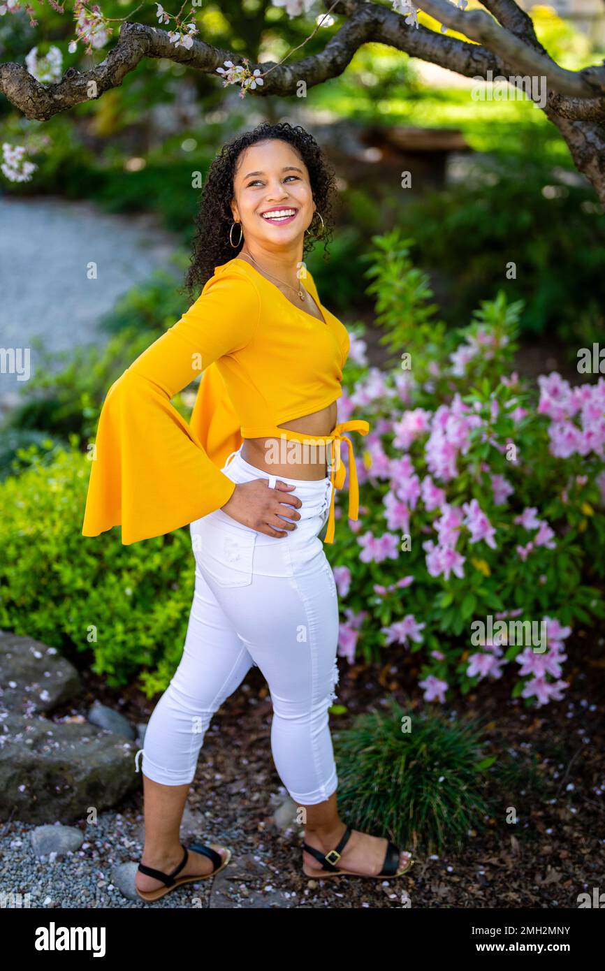 Down-Angle-Porträt einer glücklichen jungen afroamerikanischen Frau in einem blühenden Garten im japanischen Stil im Frühling Stockfoto