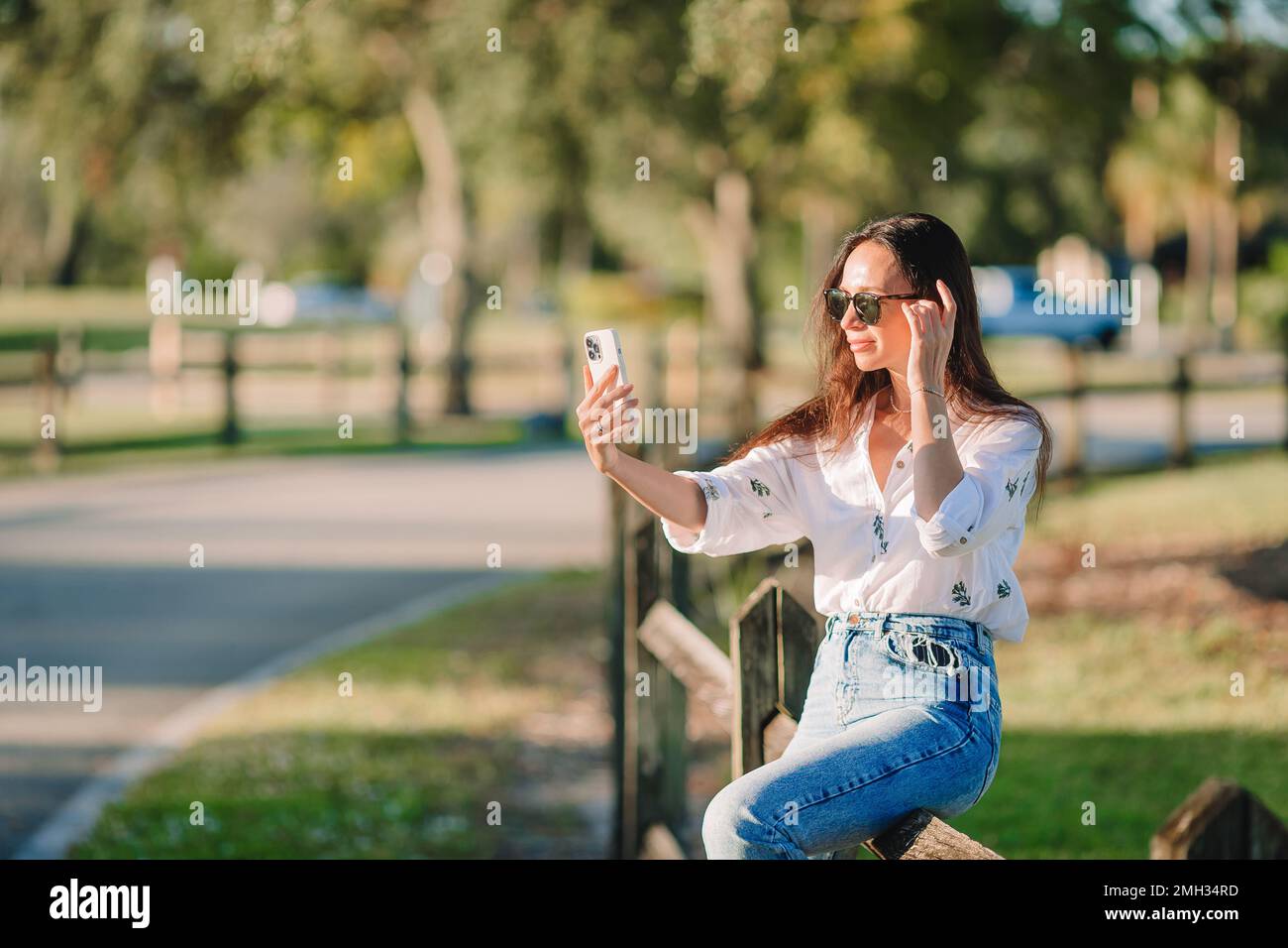 Junge Frau, die im Park ein Handy benutzt Stockfoto