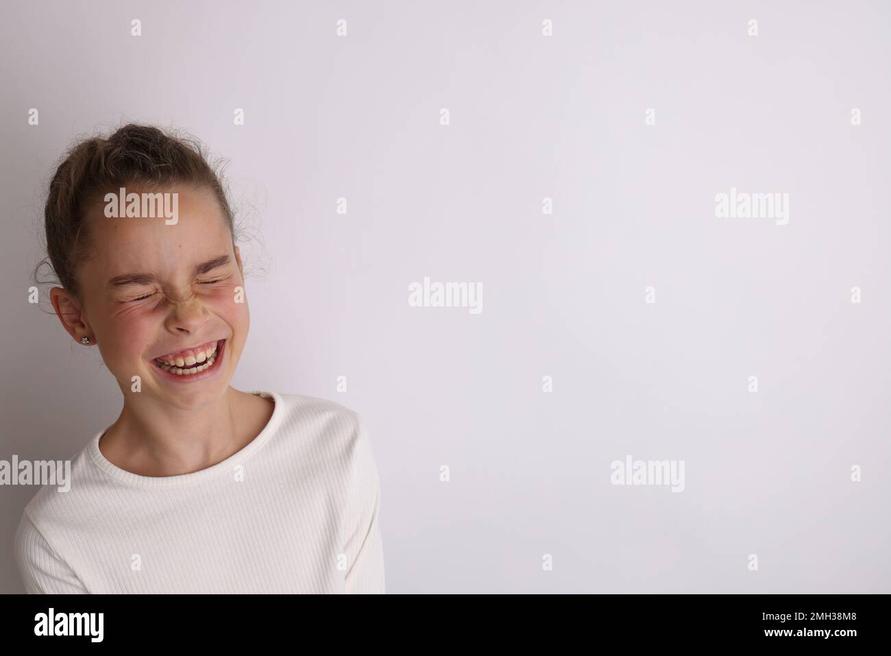 Kleines emotionales Teenager-Mädchen im weißen Hemd, 11, 12 Jahre alt, auf isoliertem weißem Hintergrund. Stockfoto