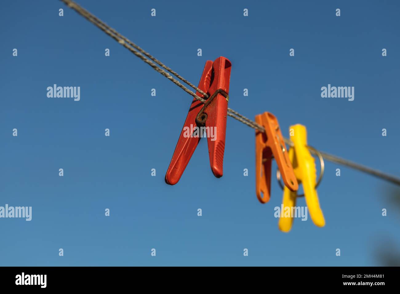 Bunte Wäscheklammern an den Kleiderbügeln. Kunststoffkleideräume in verschiedenen Farben. Stockfoto