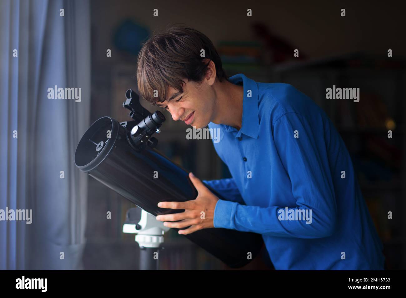 Junger Mann, der Sterne durch das Teleskop betrachtet. Ein Teenager, der den Nachthimmel beobachtet. Teenager, der Planeten und Mond beobachtet. Astronomie-Hobby. Stockfoto