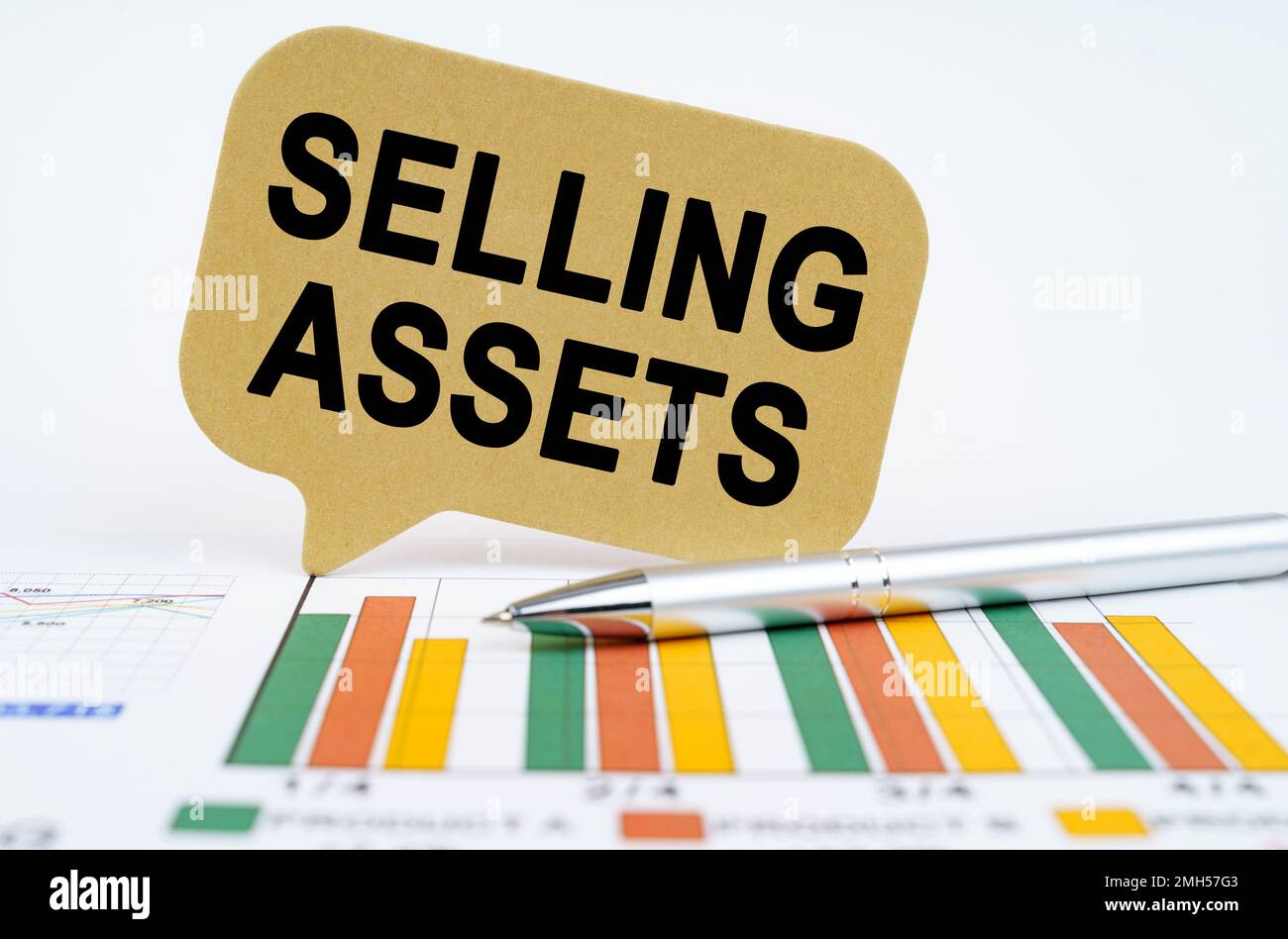 Geschäftskonzept. Auf den Finanzplänen befinden sich ein Stift und ein Schild mit der Aufschrift „Selling Assets“ Stockfoto