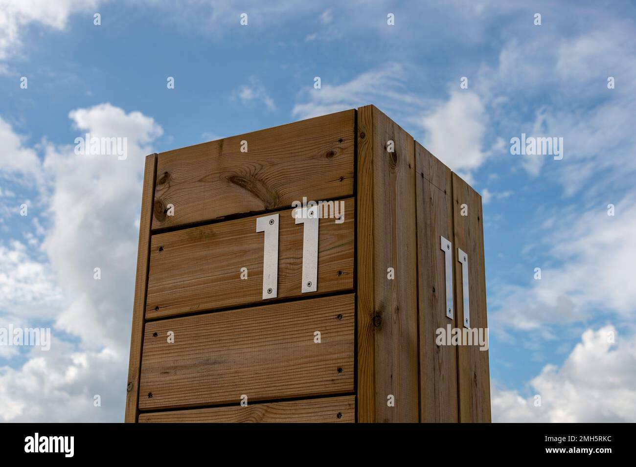 Nummer 11 in Edelstahl auf einem Holzhintergrund vor einem Himmel. 11 Stockfoto