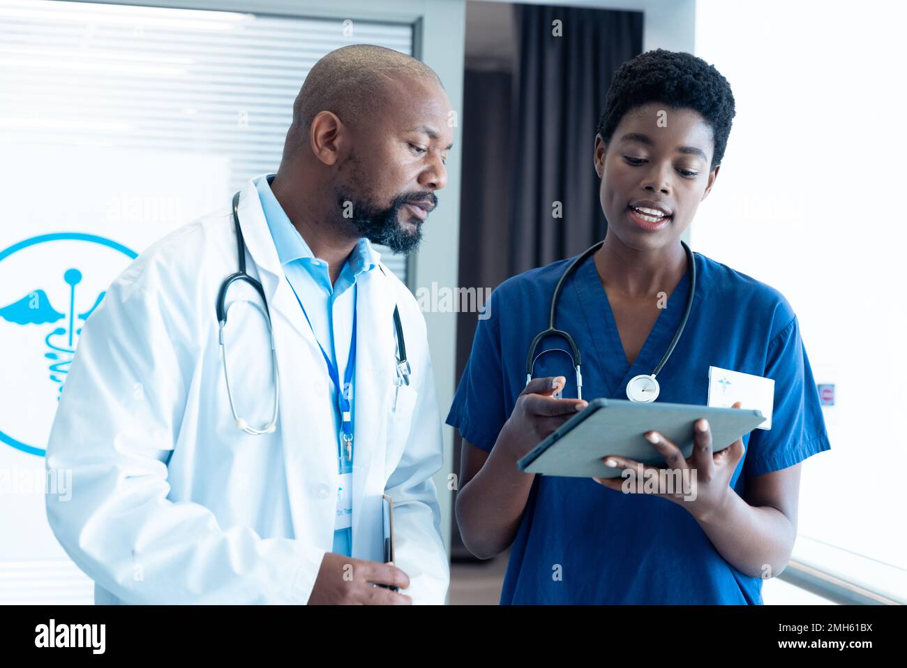 afroamerikanischer Arzt und Ärztin, die Tabletten verwenden, im Krankenhaus mit Kopierraum sprechen Stockfoto