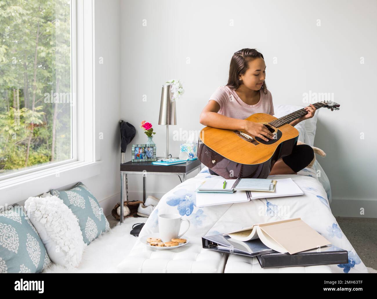 Ein Teenager-Mädchen in ihrem Schlafzimmer, das mit einer Gitarre herumtrampelt. Stockfoto