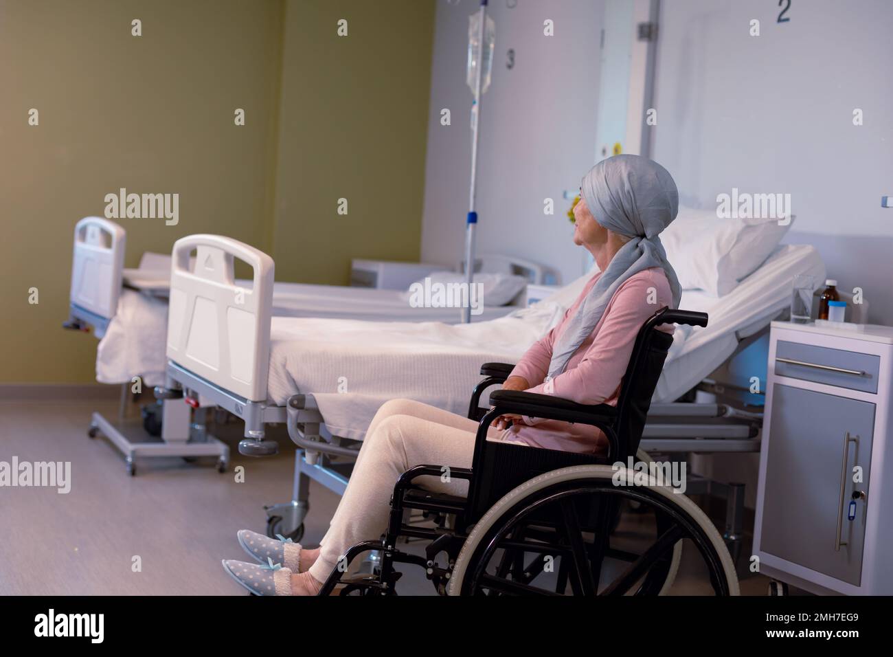 Leitende Kaukasierin weibliche Krebspatientin trägt Kopftuch im Rollstuhl im Krankenhaus Stockfoto