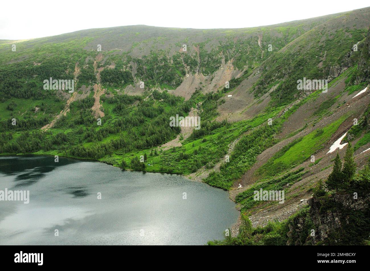 Ein großer und tiefer See in einem intermountain-Becken mit Schneeresten an den Hängen unter einem bewölkten Sommerhimmel. Iwanowskie-Seen, Chakassien, Sibirien, R. Stockfoto