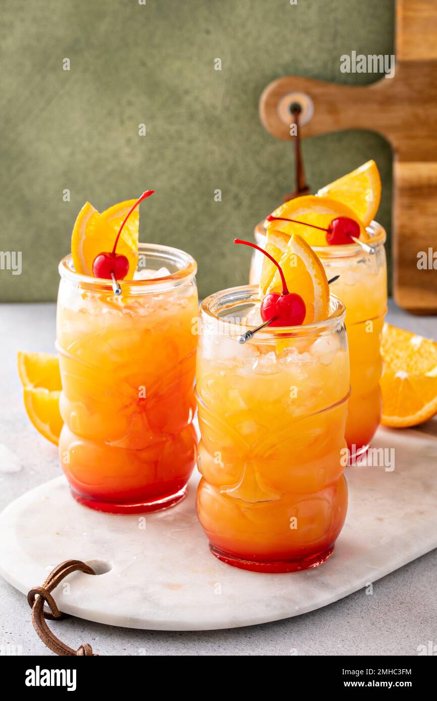 Rumpunsch in Tiki-Gläsern mit Orangenscheiben und einer Kirsche Stockfoto