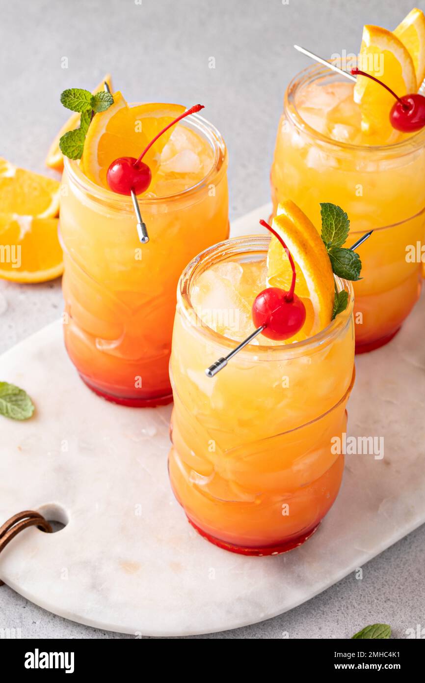 Rumpunsch in Tiki-Gläsern mit Orangenscheiben und einer Kirsche Stockfoto