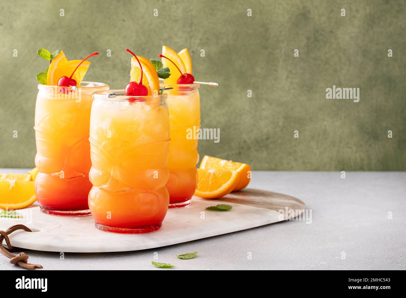 Rumpunsch in Tiki-Gläsern mit Orangenscheiben und einer Kirsche Stockfoto