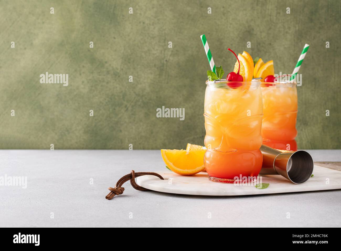 Rumpunsch in Tiki-Gläsern mit Orangenscheiben und einer Kirsche Stockfoto