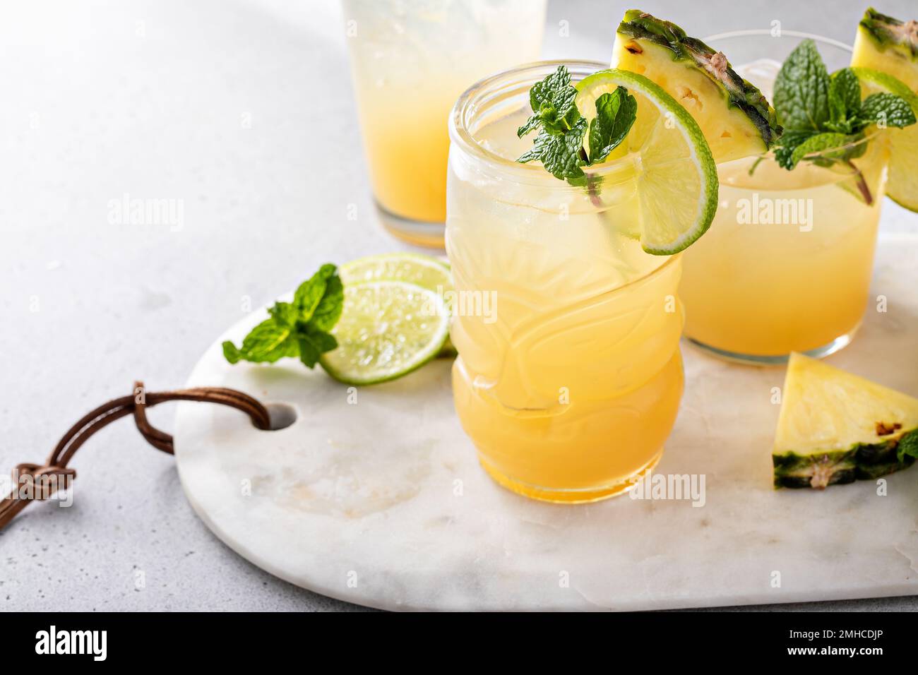 Mai Tai-Cocktail in verschiedenen Gläsern garniert mit Ananas und Limette Stockfoto