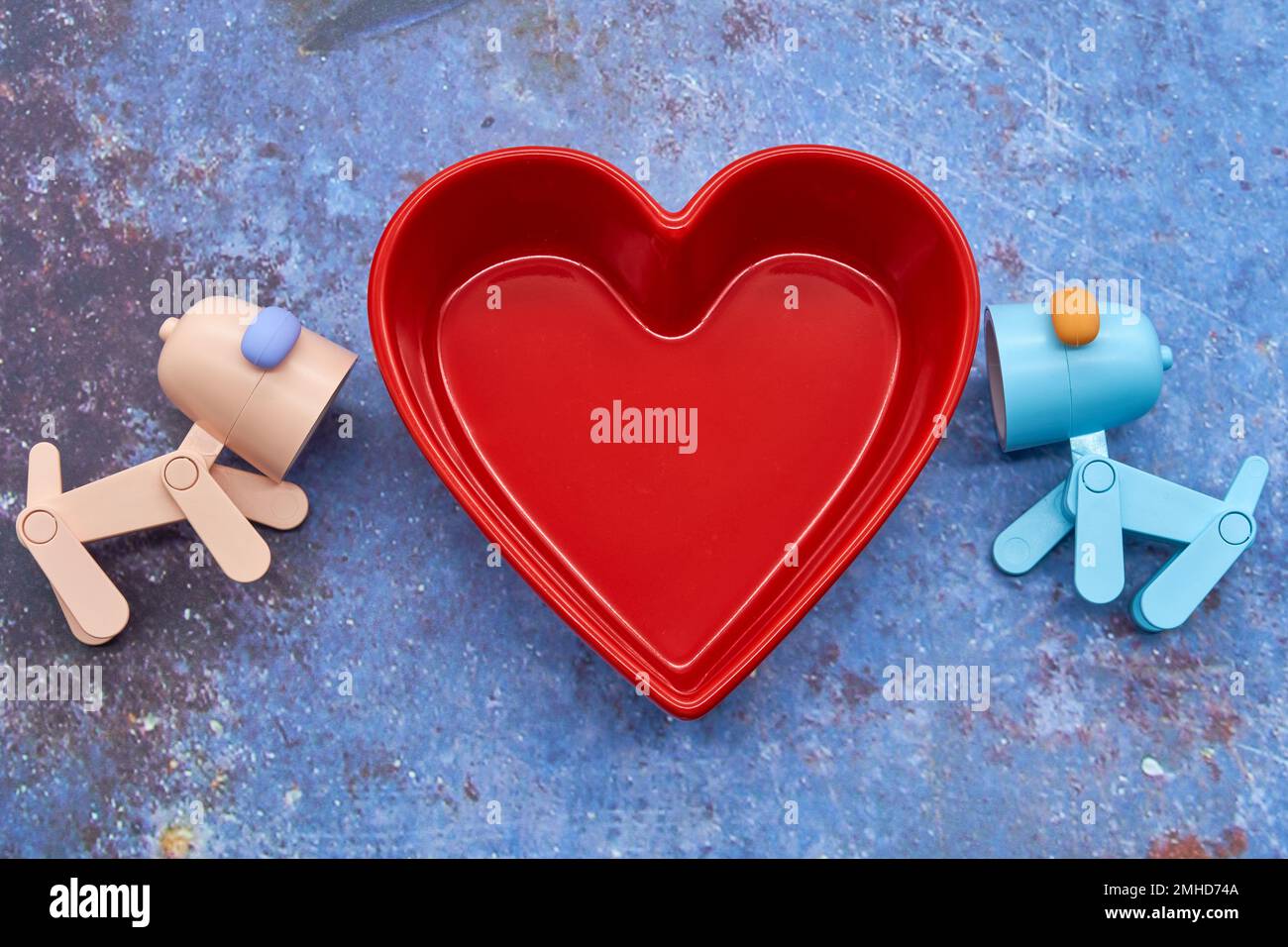 Herzmuschelschale mit zwei Spielzeughunden, die darauf gerichtet sind. Liebe verbunden valentinstag Betonhintergrund Stockfoto
