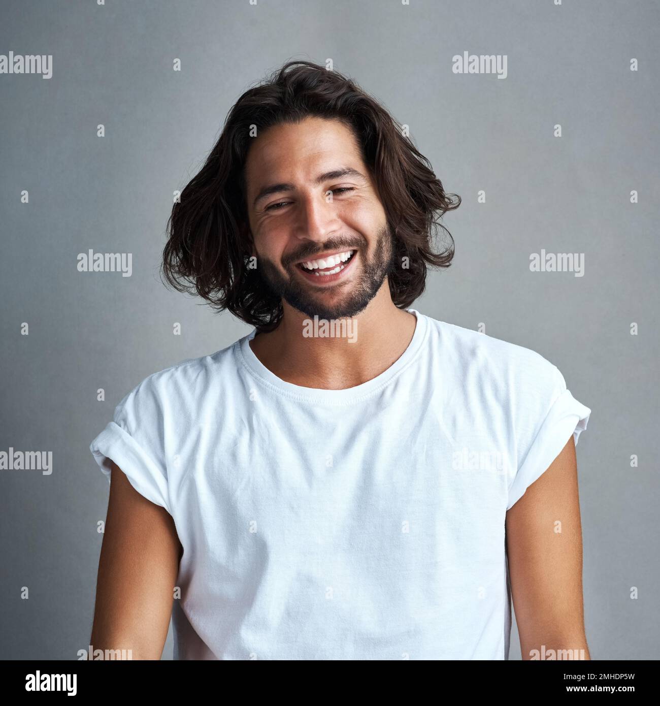 Noch attraktiver, wenn er lächelt. Studiofoto eines gutaussehenden jungen Mannes, der vor grauem Hintergrund posiert. Stockfoto