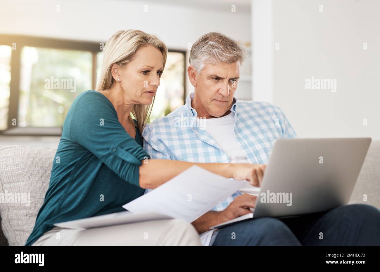 Sind diese Zahlen korrekt? Ein reifes Paar, das sein Haushaltsbudget zu Hause macht. Stockfoto