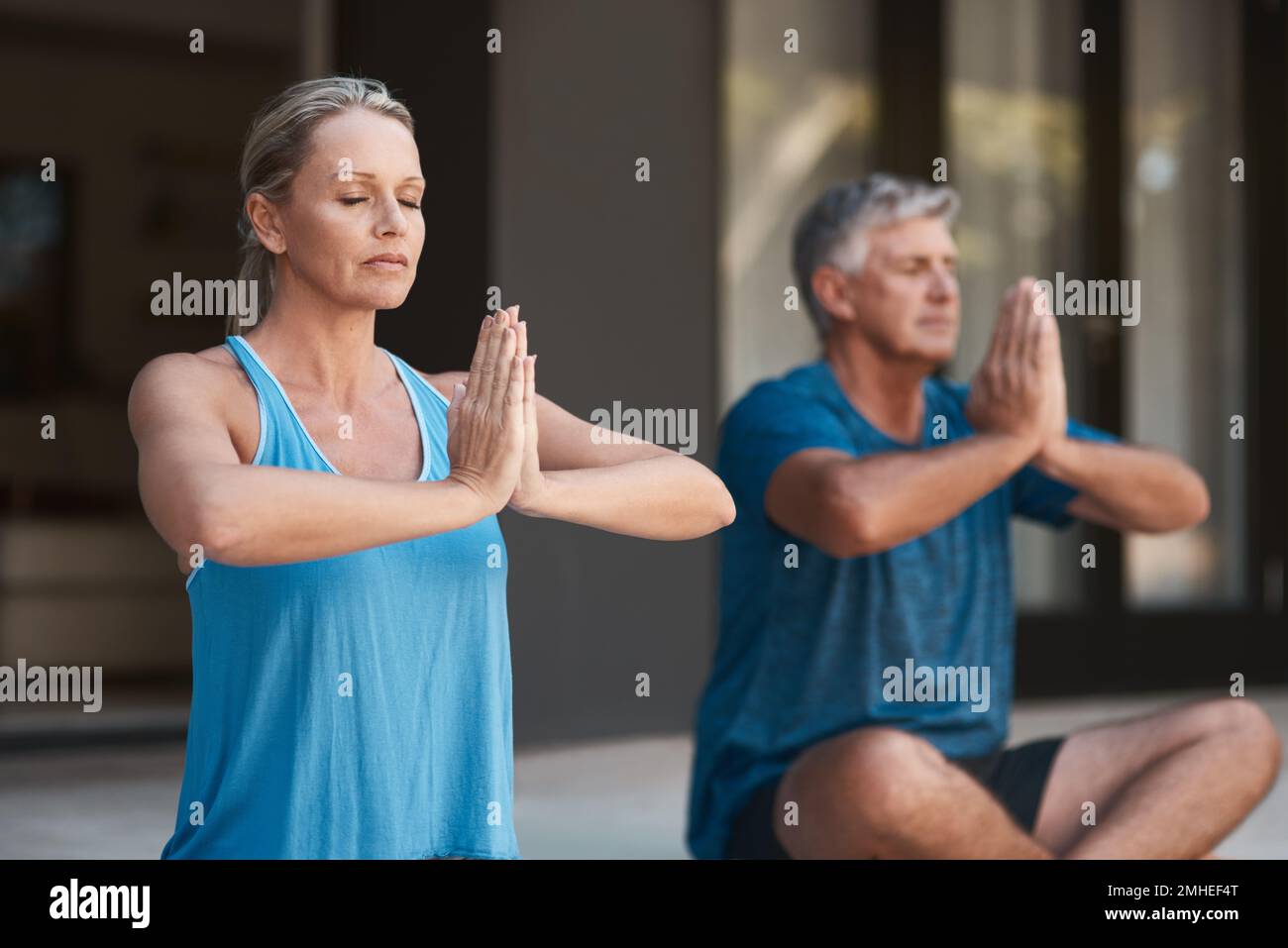 Konzentriere den Geist und du wirst Frieden finden. Ein erwachsenes Paar, das friedlich Yoga-Pose macht, mit gekreuzten Beinen und Händen. Stockfoto