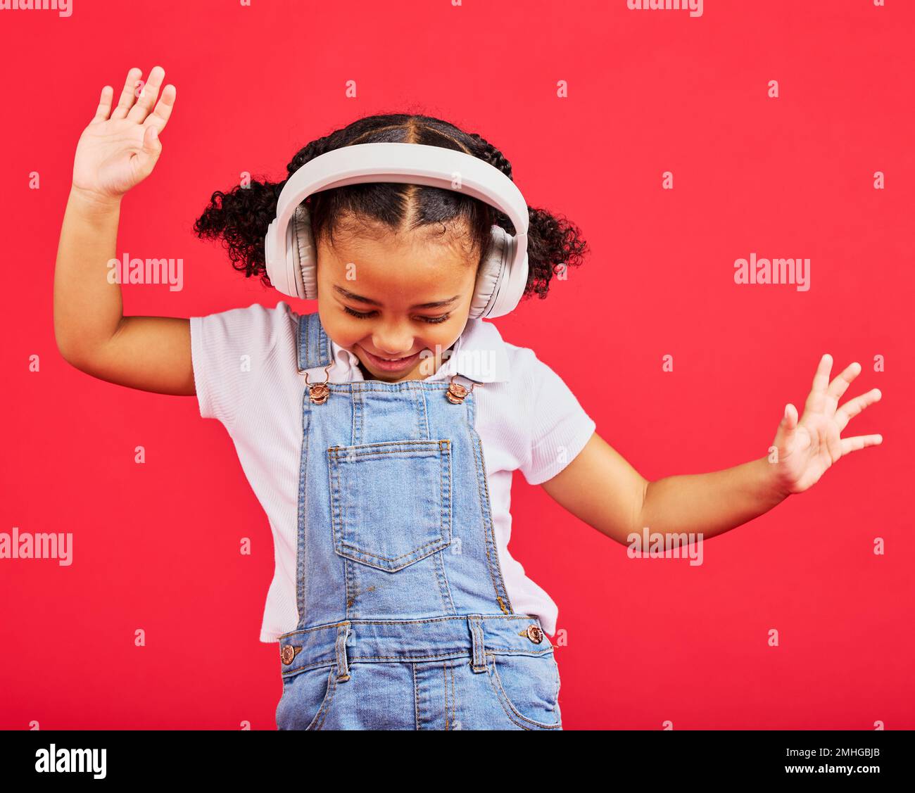 Tanzen, Energie- und Kinder- und Musik-Kopfhörer, lustiges Radio und laute Podcasts auf isoliertem roten Hintergrund oder Studiohintergrund. Lächeln, glückliches Kind und Mädchen Stockfoto
