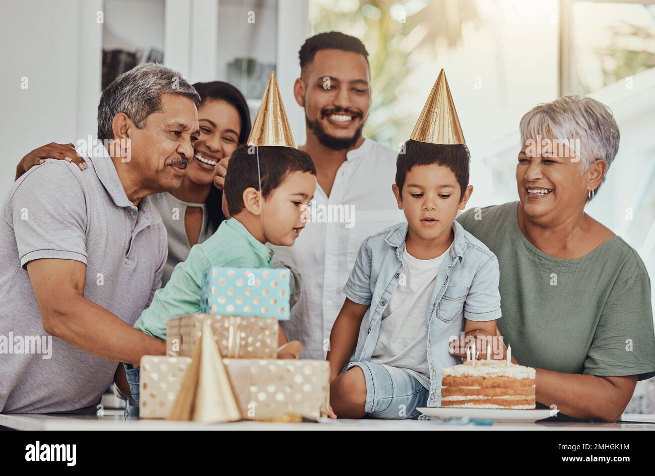 Geburtstag, Feier und Zwillinge blasen die Kerzen auf einem Kuchen auf ihrer Party mit der Familie. Glücklich, aufgeregt und Kinder mit ihren Eltern und Stockfoto