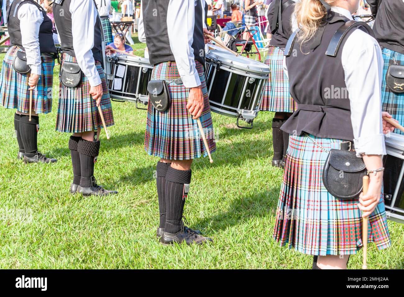 Schottische Bandtrommler-Musiker marschieren bei Highland-Spielen, ein Foto von der Rückseite des Veranstaltungsortes im Freien, Sommertag am blauen Himmel. Stockfoto
